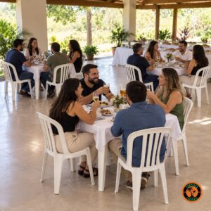 Colegas de trabalho em conjuntos de mesa e cadeiras plásticas brancas numa confraternização em área coberta