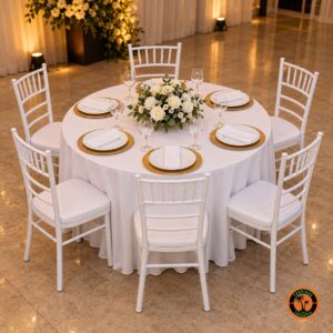 Mesa redonda de casamento para 6 lugares com o tampão de 1,20 m, toalha branca, sousplats dourados e cadeiras Tiffany brancas