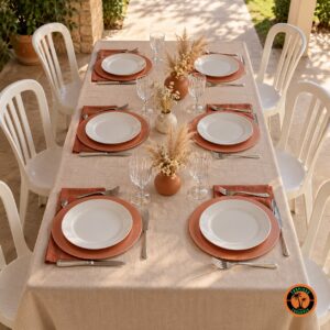 Mesa com sousplats rosê, guardanapos terracota e cadeiras plásticas brancas