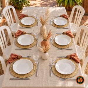 Mesa com sousplats dourados foscos, guardanapos terracota e cadeiras plásticas brancas