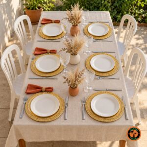 Mesa com sousplats dourados com frisos, guardanapos terracota e cadeiras plásticas brancas