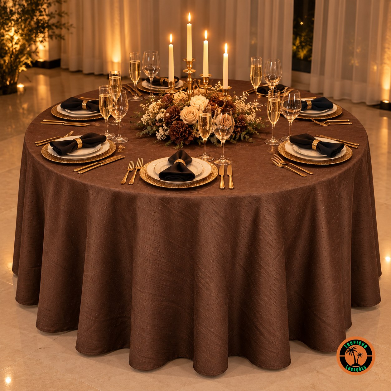 Mesa redonda com toalha lisa marrom chocolate, candelabro dourado com velas e guardanapos pretos