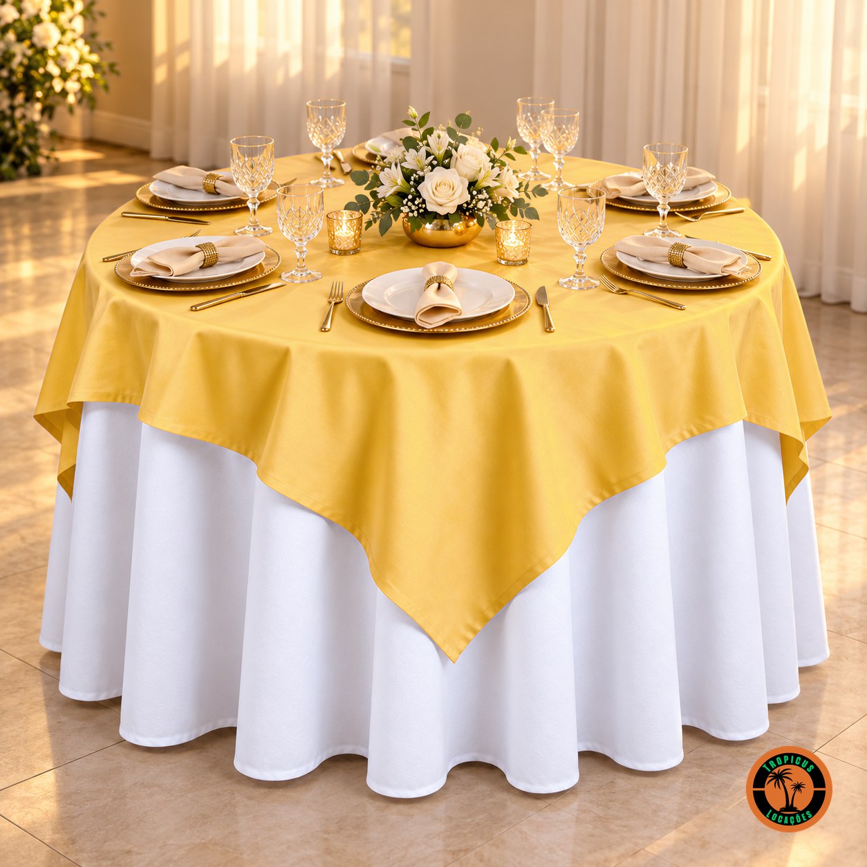 Mesa redonda com cobre-mancha amarelo-ouro sobre toalha branca, sousplats dourados e rosas brancas