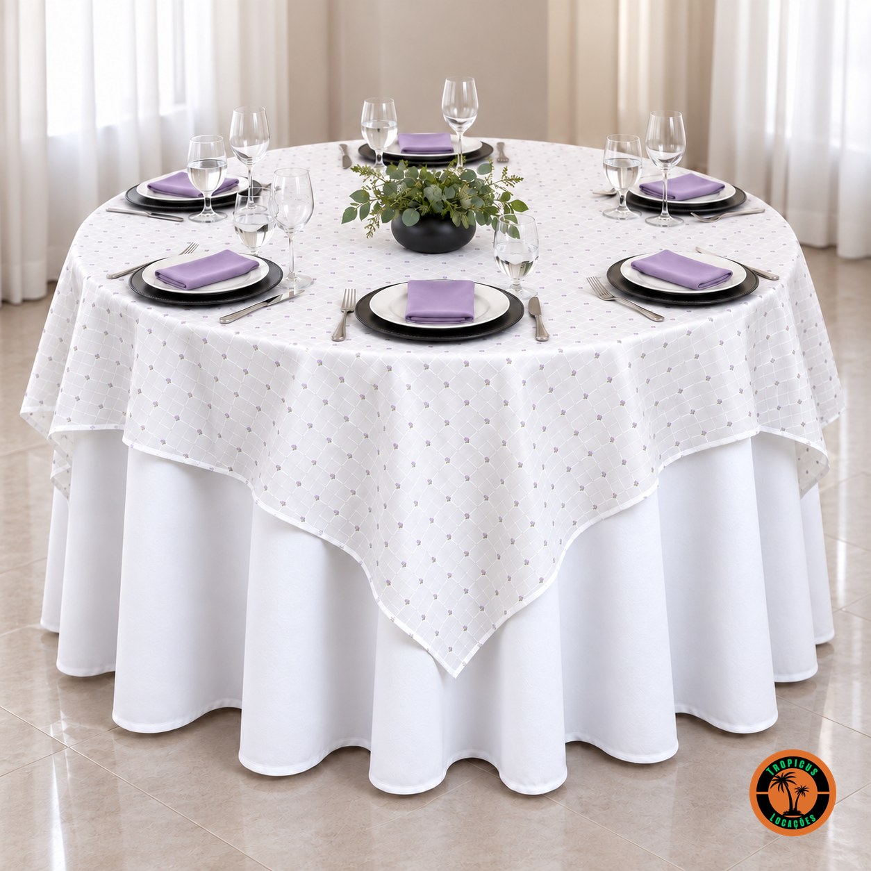 Mesa redonda com cobre-mancha branco de florzinhas lilás, sousplats pretos e guardanapos lilás