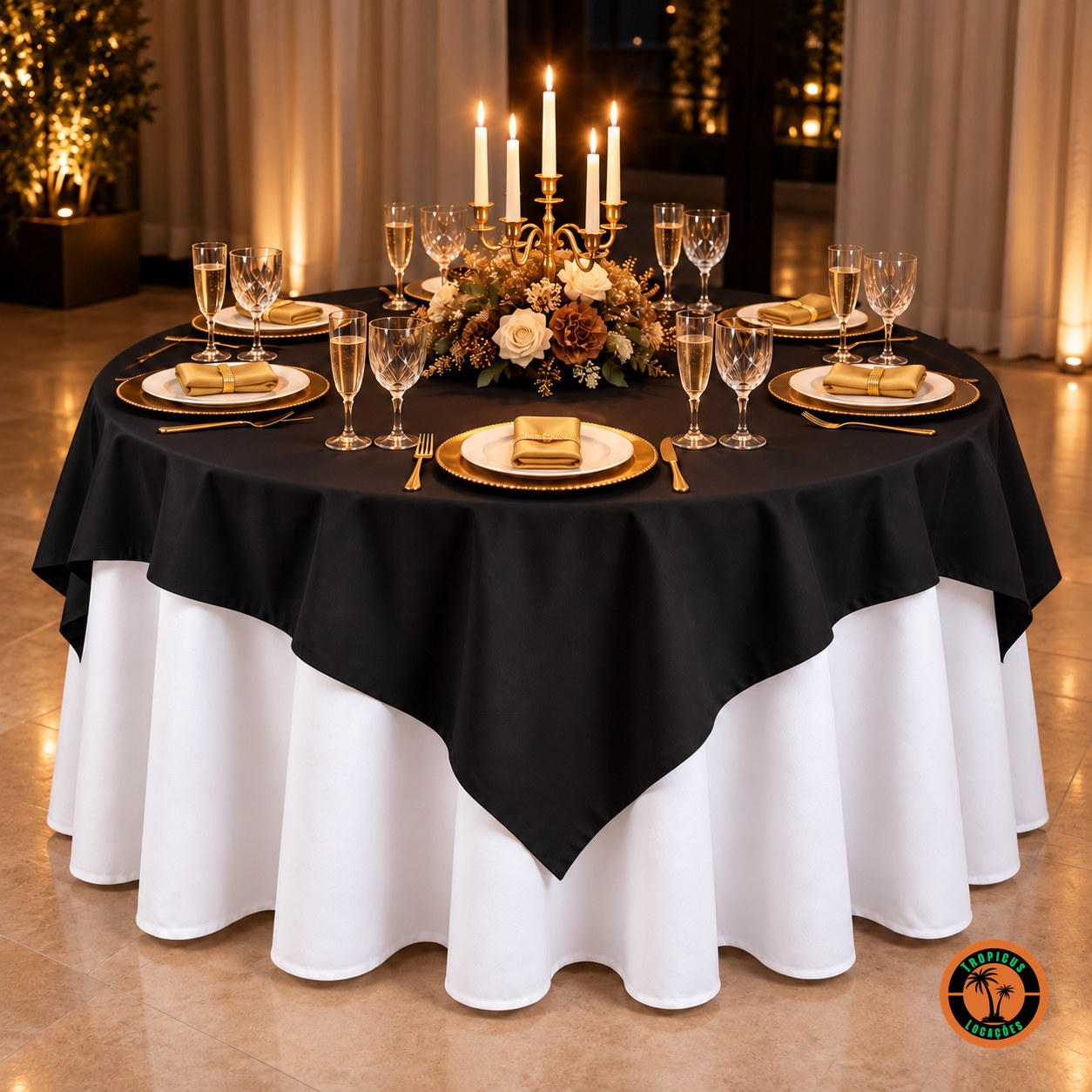 Mesa redonda com cobre-mancha preto sobre toalha branca, candelabro com velas e guardanapos dourados