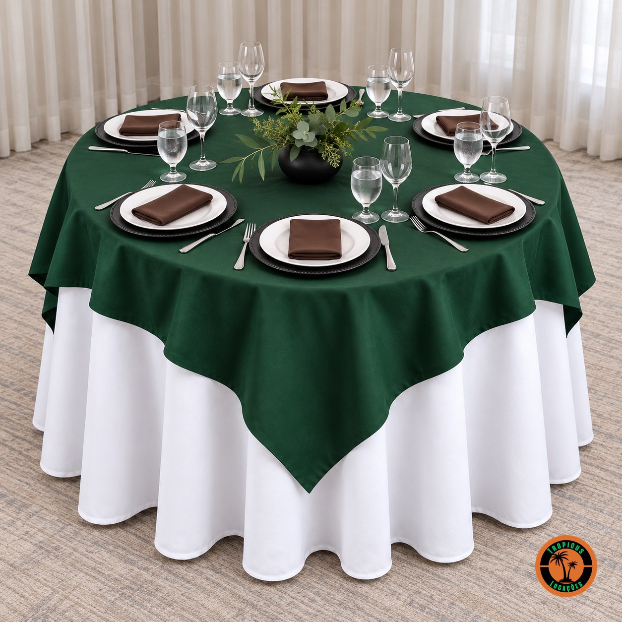 Mesa redonda com cobre-mancha verde-escuro sobre toalha branca, sousplats pretos e guardanapos marrons