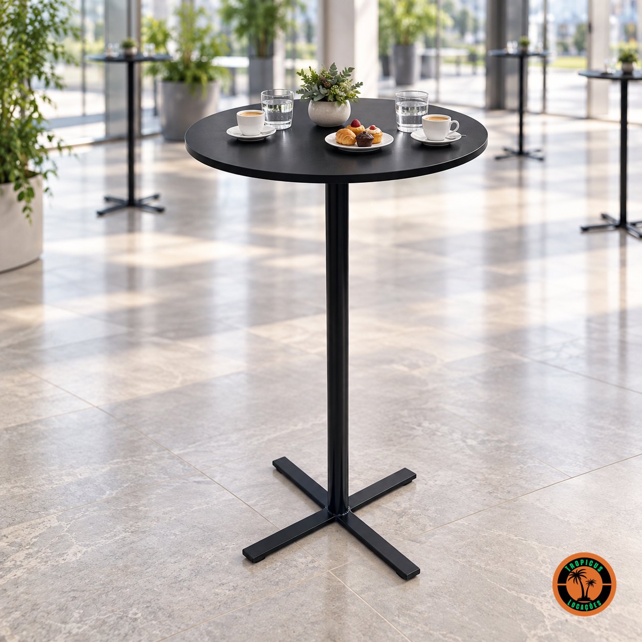Mesa bistrô alta preta num hall corporativo, com xícaras de café, copos de água, doces e uma planta