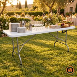 Mesa dobrável branca como apoio de buffet num jardim, com pratos, talheres, taças, frios e flores do campo